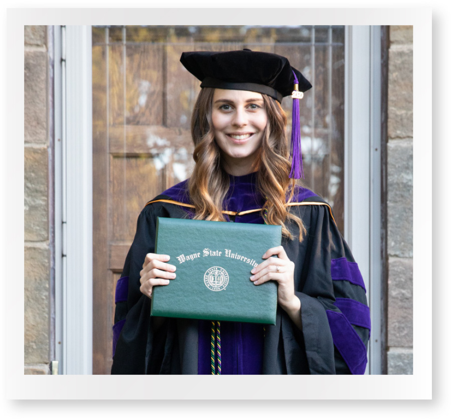 polaroid of female student at her home wearing cap and gown and holding her degree