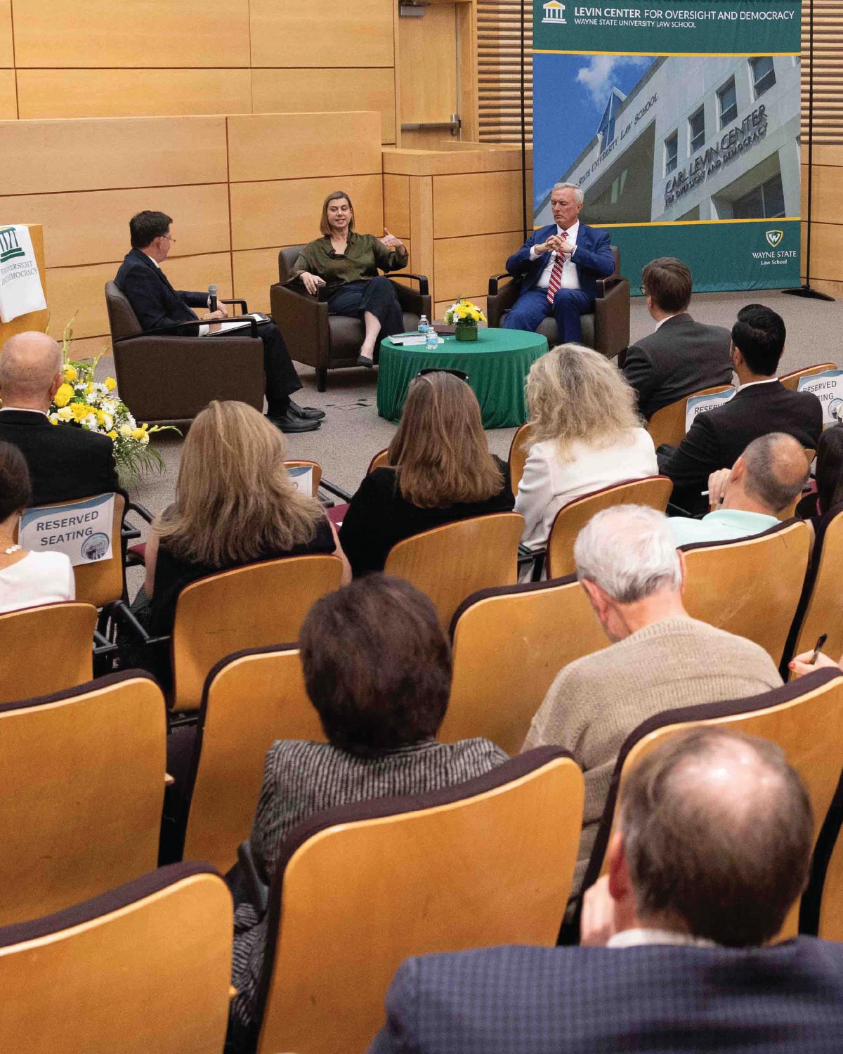 speakers in chairs having conversation during event in school auditorium