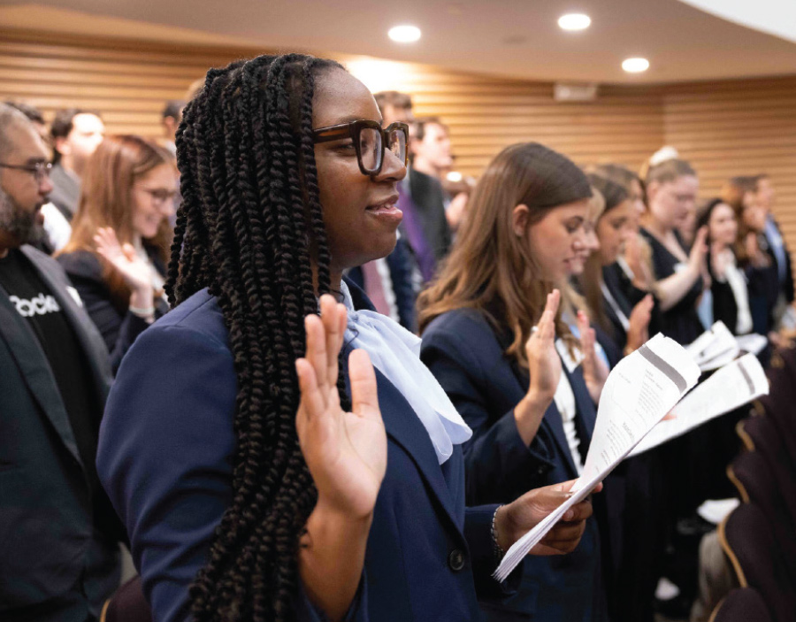 group of students standing at chairs with right hands up