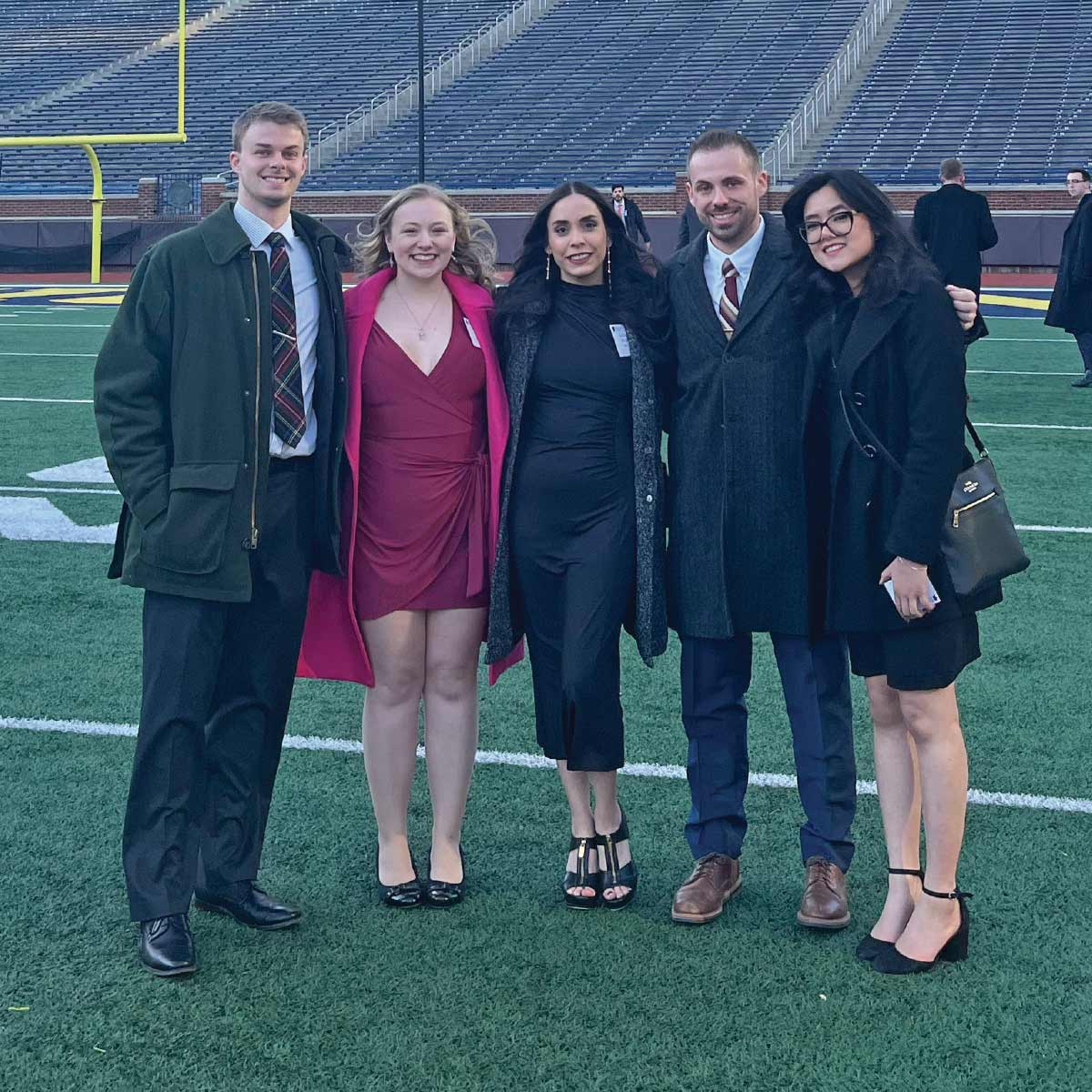 Five people smiling on a football field