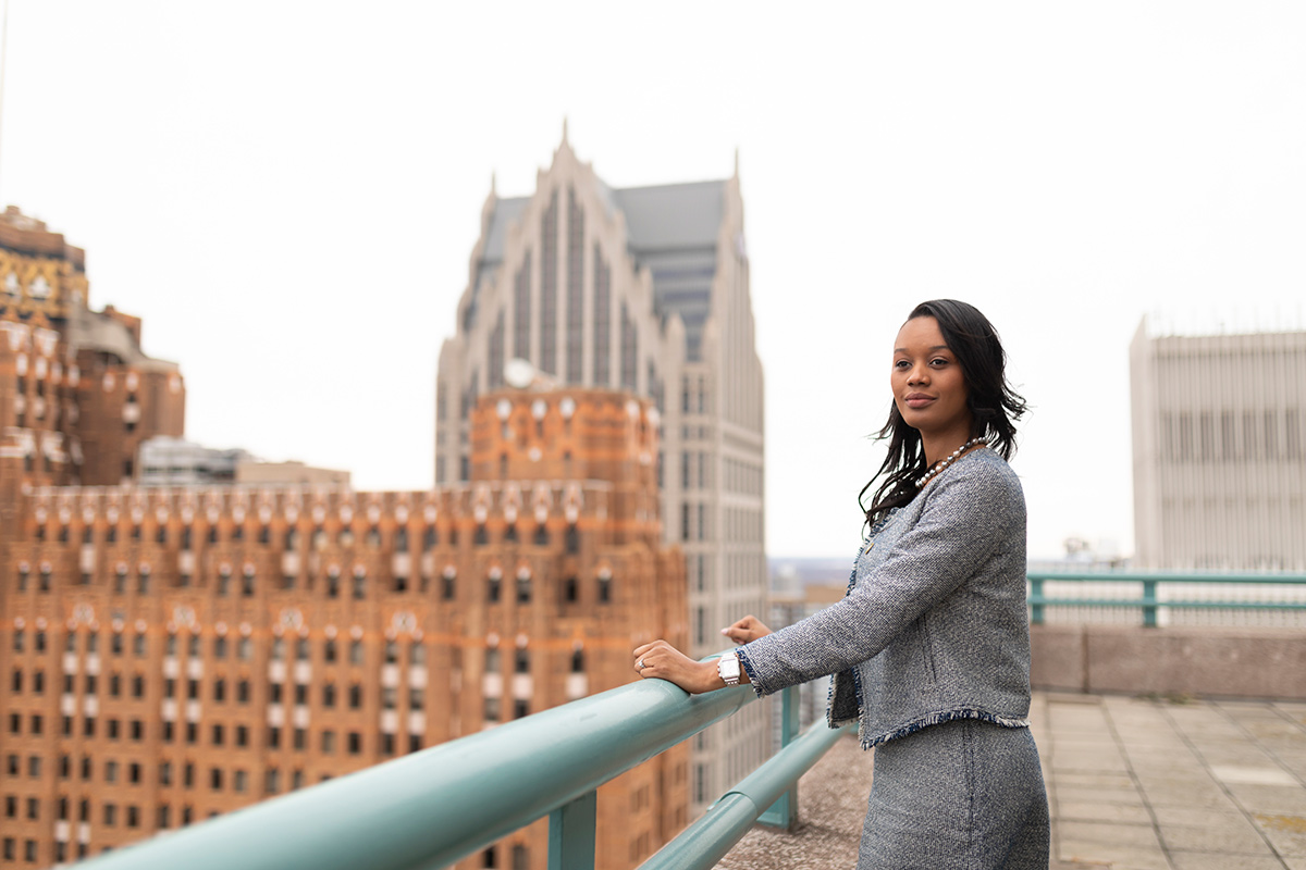 A woman stands on a rooftop overlooking a city skyline.
