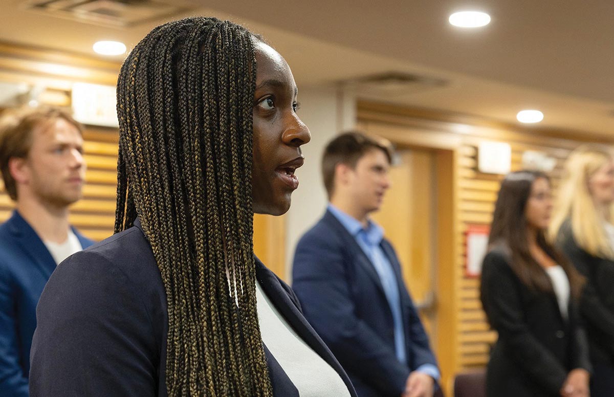 A woman speaks while standing in a line of people in professional attire.